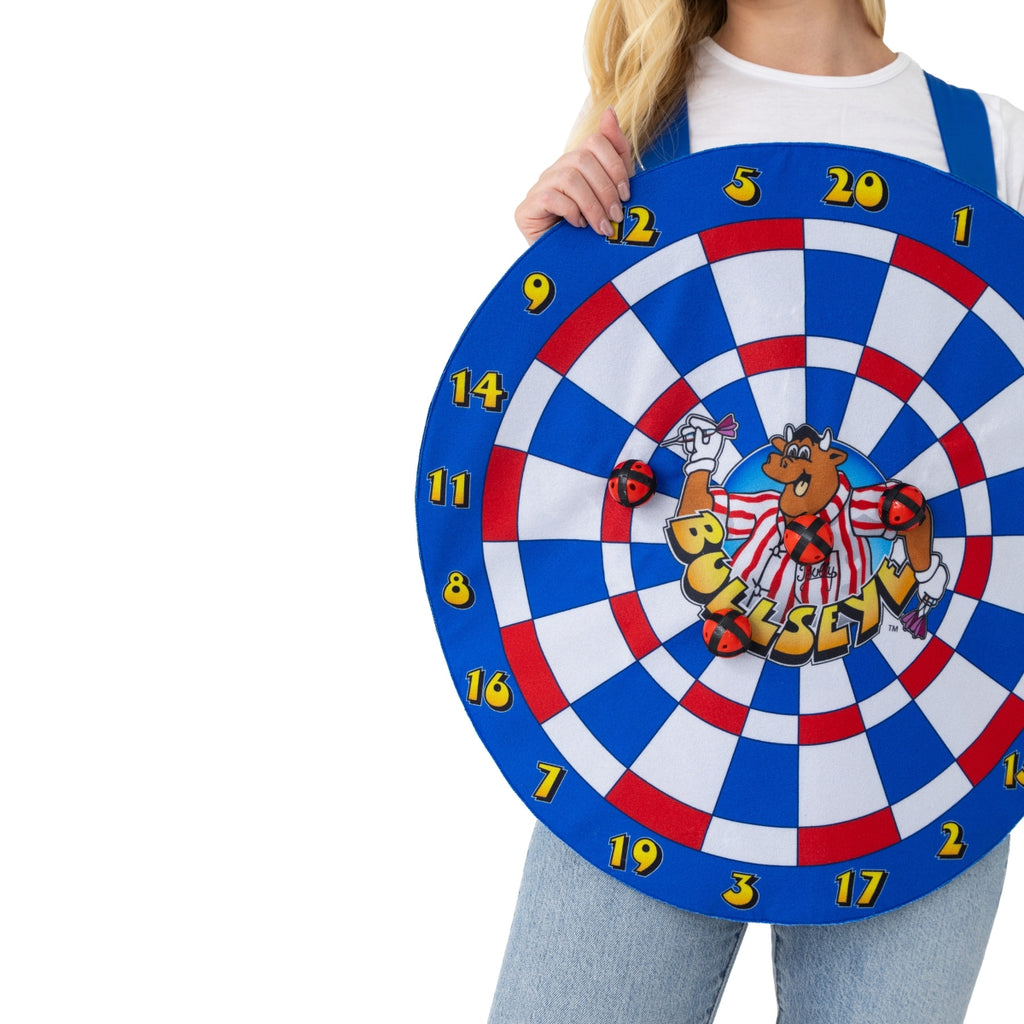 A woman holds the Bullseye Bully Dartboard Tabard with Velcro Balls by Professional Darts Corporation, featuring blue, red, and white sections, a cartoon bull in the center, and soft Velcro balls attached—great for 80s TV costumes or fans.