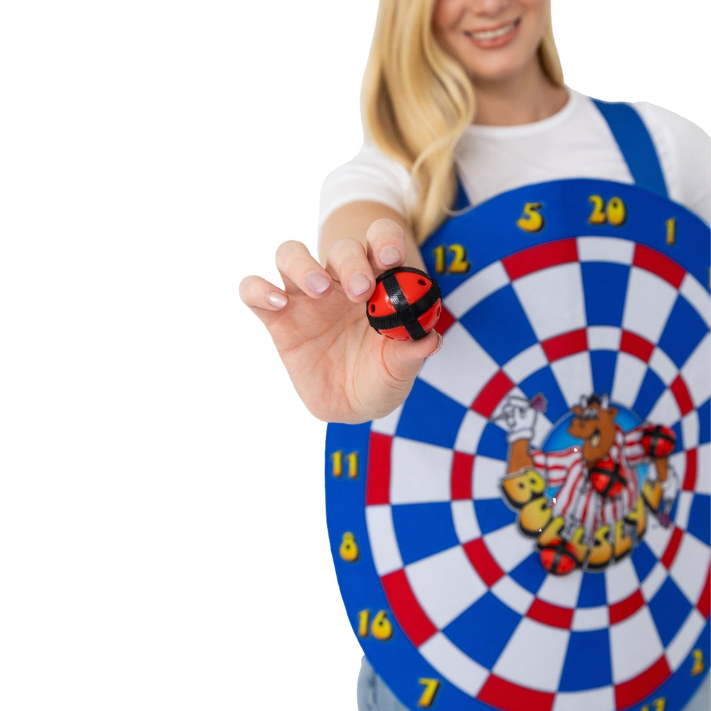 A smiling woman in a Bullseye Bully Dartboard Tabbard from Professional Darts Corporation holds a red and black Velcro ball; the dartboard features blue, red, and white rings with cartoon graphics—perfect for Official Bullseye fans.