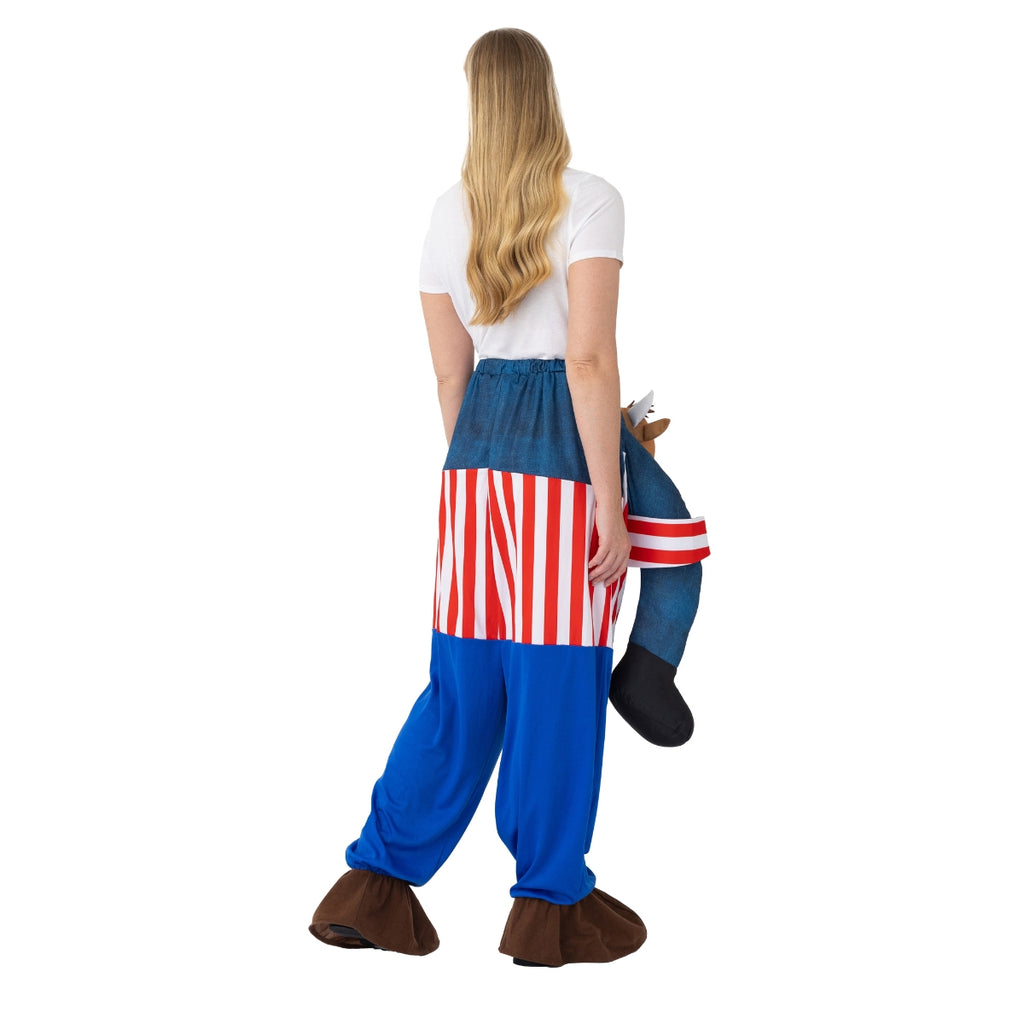 A person with long blonde hair wears the Bullseye Ride on Bully Costume by Professional Darts Corporation, creating the illusion of being carried by a brown horse with a red and white saddle, facing away from the camera.